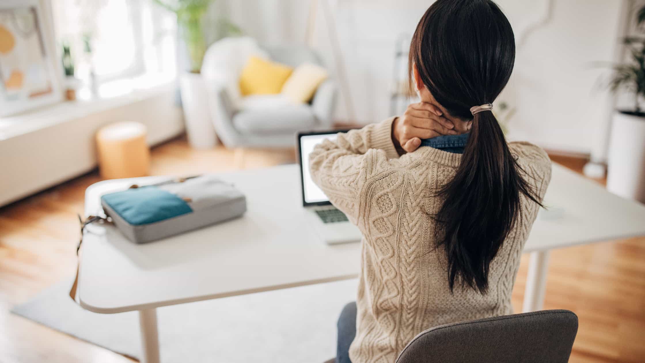 Hurting your spine - a woman sitting at a desk with her back pain