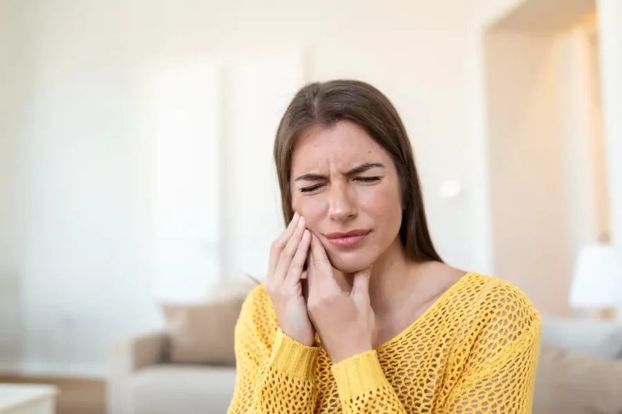 Woman holding jaw due to TMJ pain