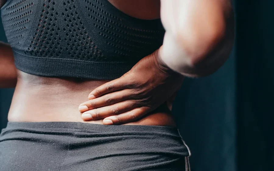 Woman holding lower back due to pain and discomfort