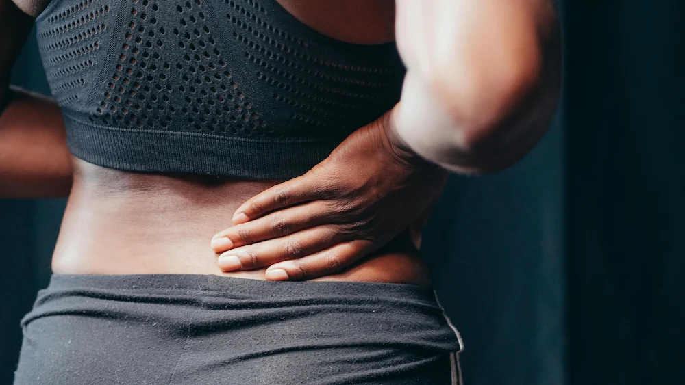 Woman holding lower back due to pain and discomfort