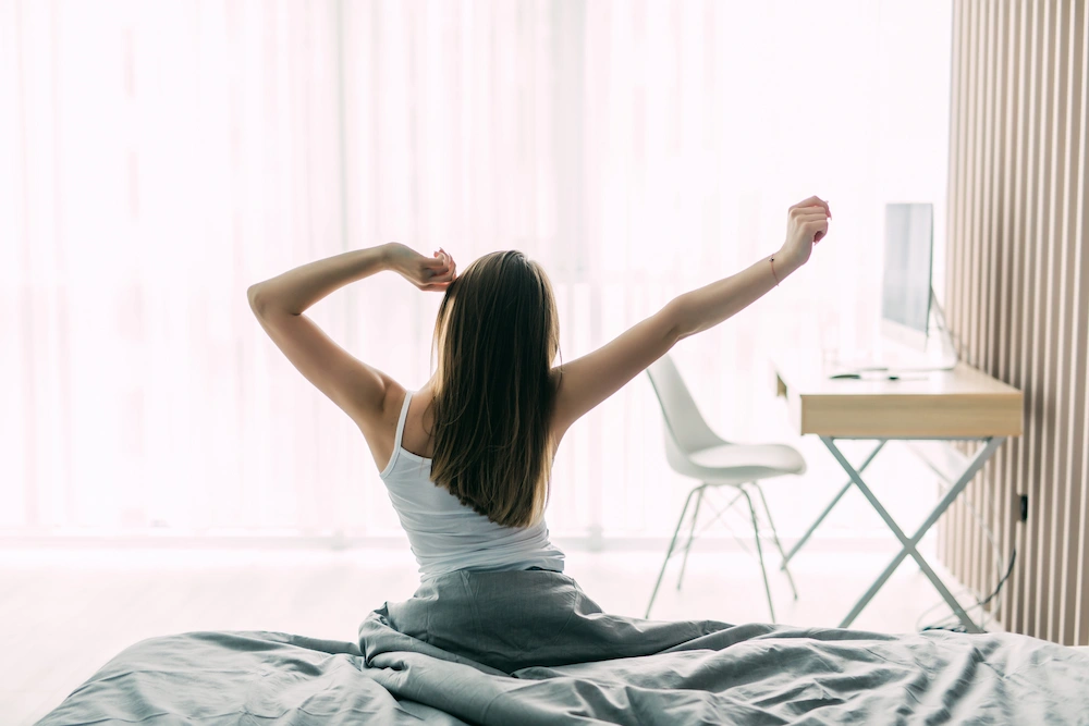 Person stretching lower back after waking up in bed