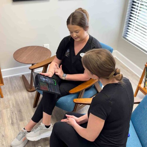 Chiropractic assistant Brittany sitting with a patient in the waiting area.
