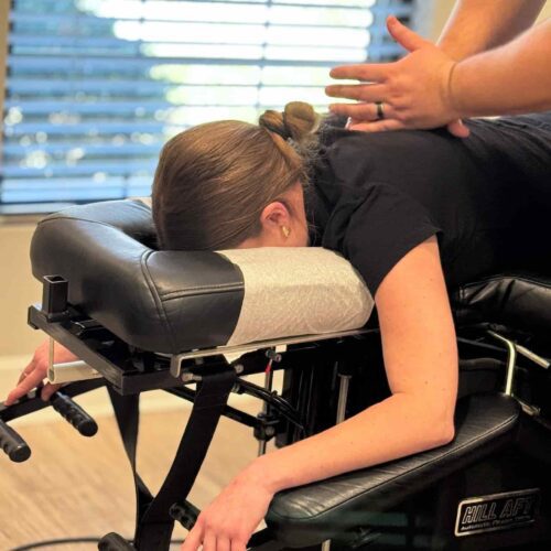 Close-up of Dr. Cameron Gentile’s hands on a patient’s upper back as they lie face down on the chiropractic table during an adjustment.