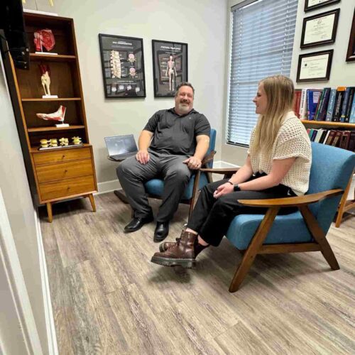 Dr. Cameron Gentile sits in a chair across from a patient in a consultation room, discussing her concerns and treatment options.