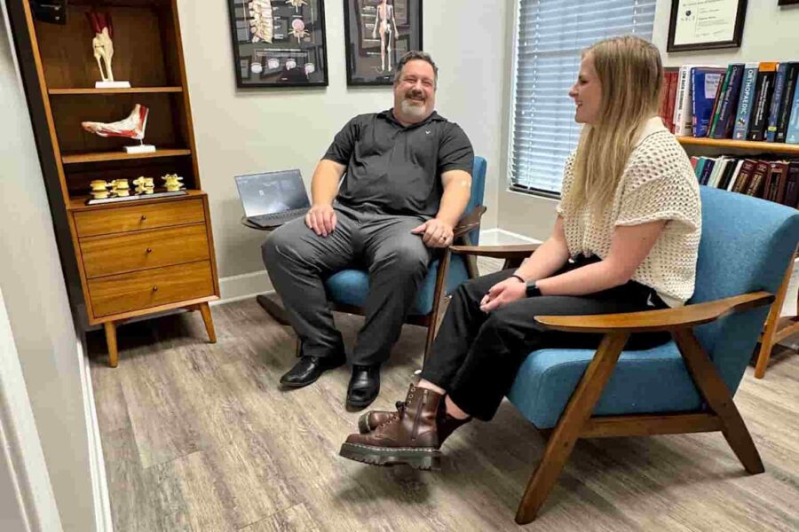 Dr. Cameron Gentile sits in a chair across from a patient in a consultation room, discussing her concerns and treatment options.