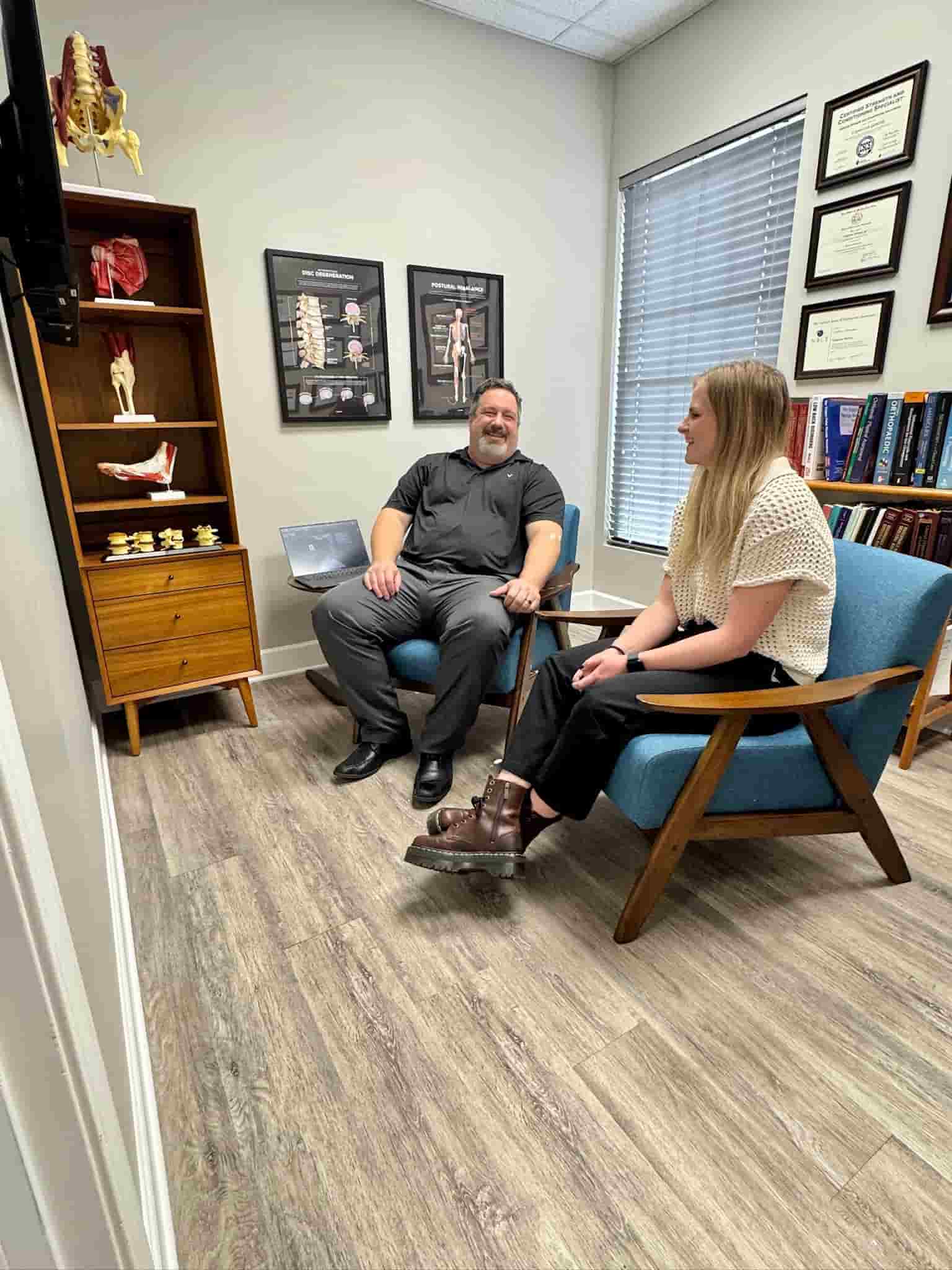 Dr. Cameron Gentile sits in a chair across from a patient in a consultation room, discussing her concerns and treatment options.