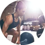 This image shows a woman in a gym setting performing a focused weightlifting exercise, highlighting strength, determination, and proper fitness technique. It’s ideal for promoting training programs, athletic performance, or gym services available in Indian Trail.
